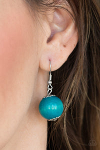 Blue wooden bead dangling from a silver fish hook earring.