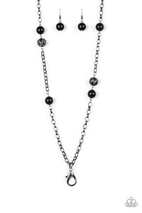 Shiny black beads and ornate gunmetal beads trickle along a bold gunmetal chain, creating a colorfully industrial look across the chest. A lobster clasp hangs from the bottom of the design to allow a name badge or other item to be attached. Features an adjustable clasp closure.  Sold as one individual lanyard. Includes one pair of matching earrings.