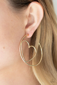 Glistening gold wire delicately bends into an airy heart frame inside a classic gold hoop, creating a flirtatious display. Earring attaches to a standard post fitting. Hoop measures approximately 2" in diameter.  Sold as one pair of hoop earrings.