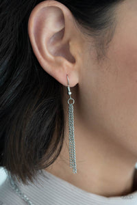 Silver chains hanging from a silver fish hook earring.