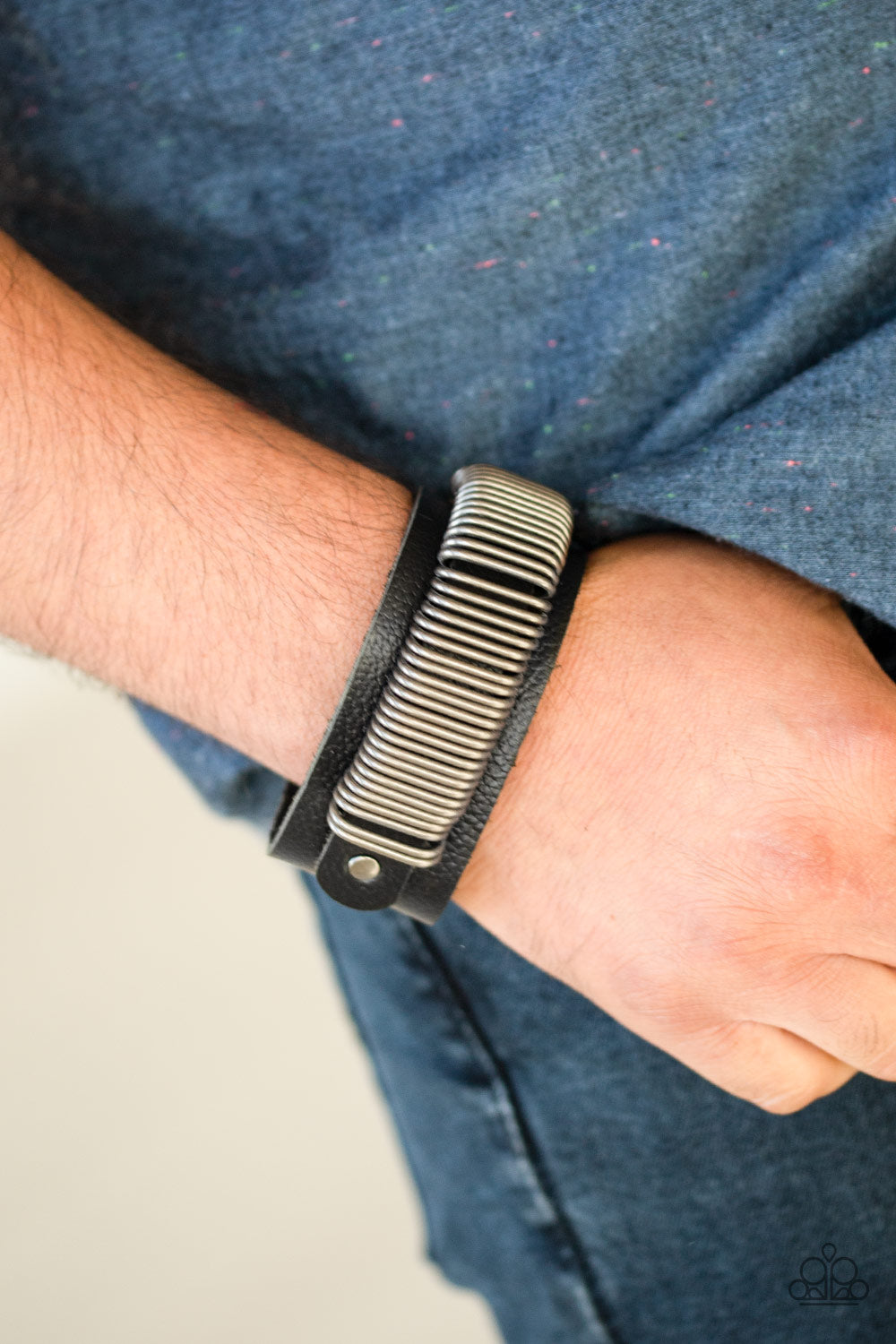 Antiqued silver rings slide along a black leather band, studded across the front of a thicker black leather band for a rustic look. Features an adjustable snap closure.  Sold as one individual bracelet.