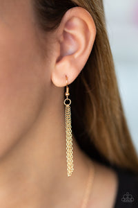 Chains hanging from a gold fish hook earring.