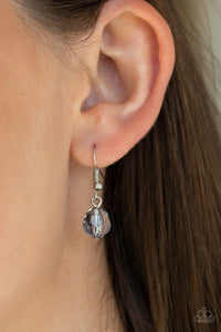 Silver disc hanging from a silver fish hook earring.