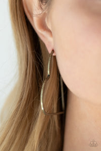 Brushed in a rustic antiqued finish, a flat brass bar delicately bends into an airy heart frame for a flirtatious finish. Earring attaches to a standard post fitting. Hoop measures approximately 2" in diameter.  Sold as one pair of hoop earrings.