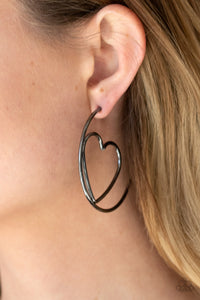 Glistening gunmetal wire delicately bends into an airy heart frame inside a classic gunmetal hoop, creating a flirtatious display. Earring attaches to a standard post fitting. Hoop measures approximately 2" in diameter.  Sold as one pair of hoop earrings.