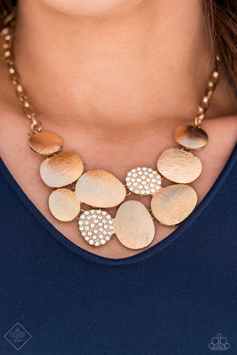 A collection of asymmetrical oval discs connect into a clustered pendant below the collar for a refined flair. Etched linear textures or white rhinestones adorn each disc, offering a gorgeous collision of texture, sheen, and sparkle. Features an adjustable clasp closure. Includes one pair of matching earrings.