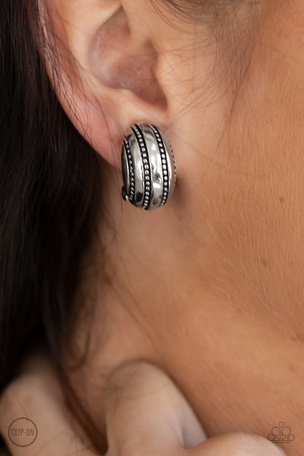 Studded in rows of linear texture, a rounded silver frame adorns the ear for a rustic look. Earring attaches to a standard clip-on fitting.  Sold as one pair of clip-on earrings.