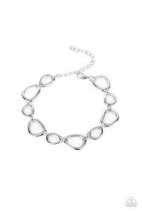 An array of irregular shaped silver rings link together and make their way around the wrist for a simple yet stylish avant-garde fashion. Features an adjustable clasp closure.