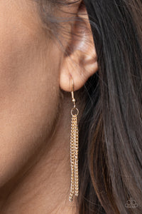 Gold chains hanging from a gold fish hook earring.