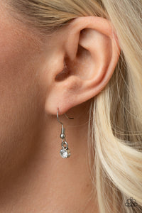 White rhinestone hanging from a silver fish hook earring.