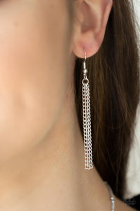 Silver chains hanging from a silver fish hook earring.