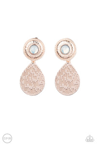 A hammered rose gold teardrop dangles from the bottom of an ornate rose gold disc that is dotted with a dreamy opal beaded center. Earring attaches to a standard clip-on fitting. Sold as one pair of clip-on earrings.