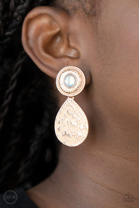 A hammered rose gold teardrop dangles from the bottom of an ornate rose gold disc that is dotted with a dreamy opal beaded center. Earring attaches to a standard clip-on fitting. Sold as one pair of clip-on earrings.