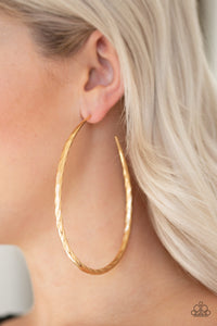 Etched in shimmer, a rippling gold bar bends into a dramatic asymmetrical hoop for a showstopping look. Earring attaches to a standard post fitting. Hoop measures 3" in diameter.  Sold as one pair of hoop earrings.