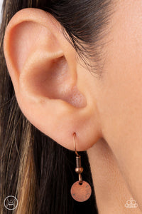 Copper disc hanging from a copper fish hook earring.