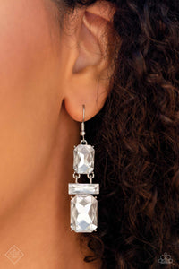 Two oversized emerald-cut gems sparkle unapologetically, increasing in size as they fall from the ear. A white gem bar, featuring sharp faceted surfaces, lays perpendicular to the blinding emerald-cut gems, separating the two and emphasizing their hinged movement. Earring attaches to a standard fishhook fitting.