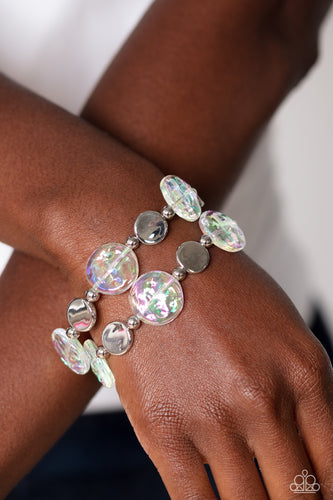 Shiny silver discs, studs, and asymmetrical clear discs featuring an iridescent shimmer coalesce around the wrist on elastic stretchy bands for an attention-grabbing shimmer. Due to its prismatic palette, color may vary.  Sold as one set of two bracelets.