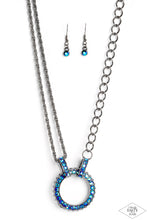 Load image into Gallery viewer, A collision of mismatched gunmetal chains gives way to a studded gunmetal pendant that has been encrusted in glittery blue UV rhinestones. The result is a gritty, industrial design with endless attitude. Features an adjustable clasp closure.  Sold as one individual necklace. Includes one pair of matching earrings.
