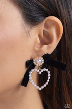 Load image into Gallery viewer, A solitaire white pearl, pressed in a white rhinestone-encrusted gold hoop, gleams atop a pearl-dotted heart frame resulting in a dazzling statement piece. A black velvet ribbon fans out from the pearly centerpiece further infusing the design with elegance. Earring attaches to a standard post fitting.  Sold as one pair of post earrings.
