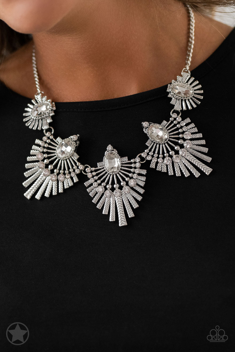Textured metal bars flare out from a mesmerizing gem, creating a fringe of fanning frames. Sprinkled with matching white rhinestones, the dazzling display falls just below the collar for a sassy Blockbuster finish. Features an adjustable clasp closure.  Sold as one individual necklace. Includes one pair of matching earrings.