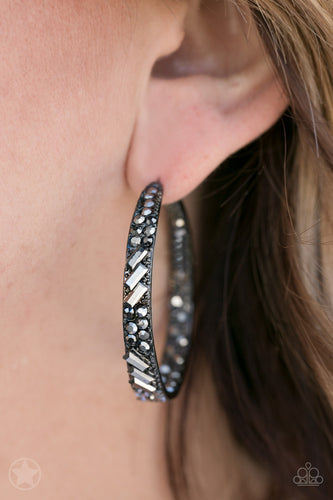 The front facing surface of a chunky black hoop is dipped in brilliantly sparkling hematite rhinestones while light-catching texture wraps around the back. The interior of the hoop features the opposite pattern, creating the illusion of a full hoop of blinding Blockbuster shimmer. Earring attaches to a standard post fitting. Hoop measures 1 3/4